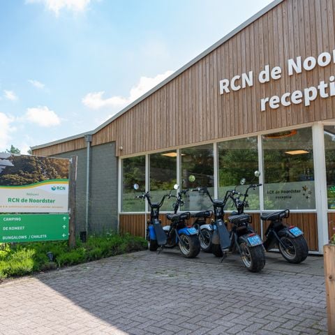 Receptiegebouw van RCN De Noordster met houten gevel en elektrische scooters ervoor