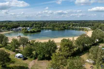 Luchtfoto van het meer met zandstrand en bos bij Vakantiepark Hunzedal