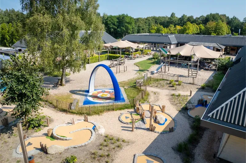 Speelplein met blauwe boog, zandpaden en minigolfbanen op Bospark Lunsbergen