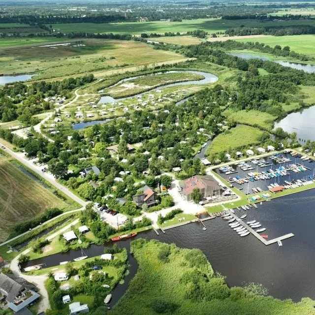 Luchtfoto van een kampeerterrein aan het Leekstermeer met een jachthaven en bos